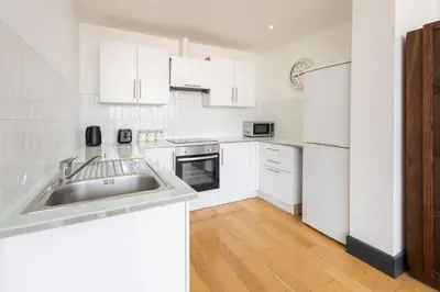 a kitchen with white cabinets and a stainless steel sink at Host & Stay - Exchange Street Living in Liverpool
