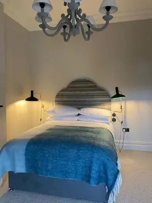 a bedroom with a bed with a blue blanket on it at Home Farm Cottage in Lytham St Annes