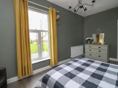 a bedroom with a checkered bed and a window at Pendle View Apartments in Blackburn