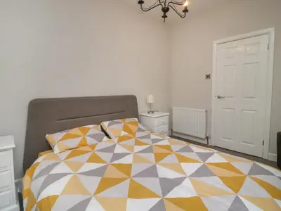 a bedroom with a bed with a colorful quilt on it at Pendle View Apartments in Blackburn