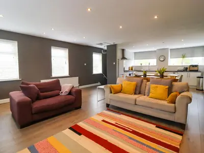 a living room with two couches and a kitchen at Pendle View Apartments in Blackburn