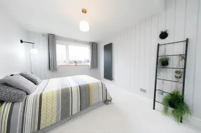 a white bedroom with a bed and a window at Beautifully styled Home with Garden in Poulton le Fylde