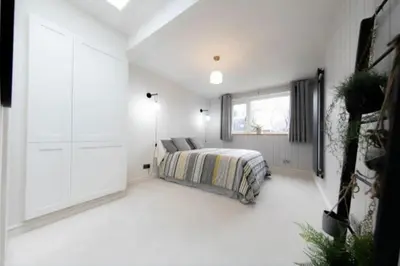 a white bedroom with a bed and a window at Beautifully styled Home with Garden in Poulton le Fylde