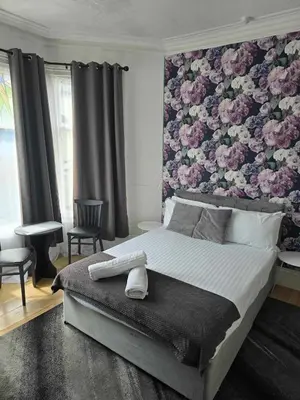 a bedroom with a large bed with a floral wall at ROSE in Blackpool