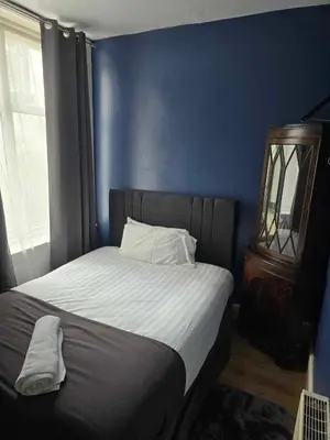 a bedroom with a bed with a blue wall at ROSE in Blackpool
