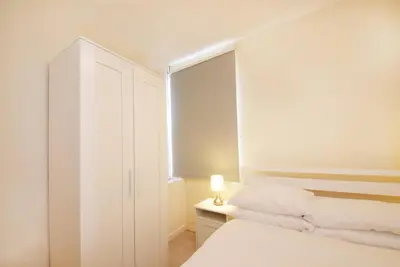 a white bedroom with a bed and a white cabinet at GuestReady Modern 2BR Home by Anfield Stadium in Liverpool