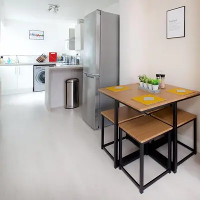 a kitchen with a table and a stainless steel refrigerator at GuestReady Modern 2BR Home by Anfield Stadium in Liverpool