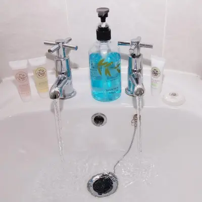 a sink with two faucets and a bottle of soap at GuestReady Modern 2BR Home by Anfield Stadium in Liverpool