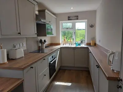 a kitchen with white cabinets and a wooden counter top at Sunnydale, Cartmel in Cartmel