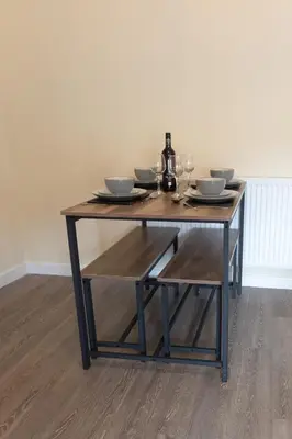 a wooden table with plates and wine glasses on it at Seaside Retreat - 2BR Apt in Southport in Southport