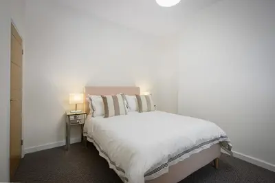 a bedroom with a white bed with a night stand at Blackpool Central Springfield Apartments Spacious Comfort in Blackpool