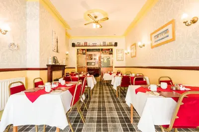 a restaurant with red and white tables and chairs at Valdene Hotel in Blackpool