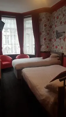 a hotel room with three beds and windows at Valdene Hotel in Blackpool