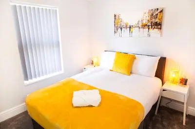 a bedroom with a large bed with a yellow blanket at 4 Bedrooms Spacious House With 2 Bathrooms Free Parking - sleeps up to 10 guests in Liverpool