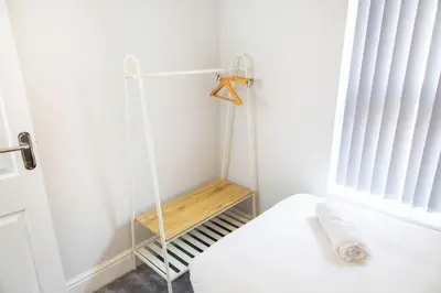 a room with a bed with a wooden shelf next to a window at 4 Bedrooms Spacious House With 2 Bathrooms Free Parking - sleeps up to 10 guests in Liverpool