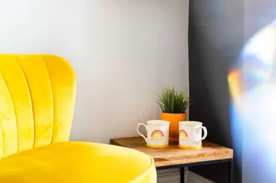 a yellow chair and two cups on a table at 4 Bedrooms Spacious House With 2 Bathrooms Free Parking - sleeps up to 10 guests in Liverpool