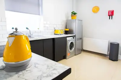 a kitchen with a washing machine and a yellow appliance at 4 Bedrooms Spacious House With 2 Bathrooms Free Parking - sleeps up to 10 guests in Liverpool