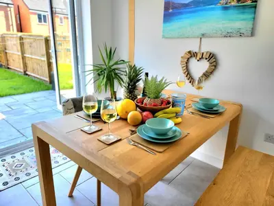 a wooden table with a bowl of fruit and wine glasses at Seaside beach themed home with garden and driveway in Lytham St Annes