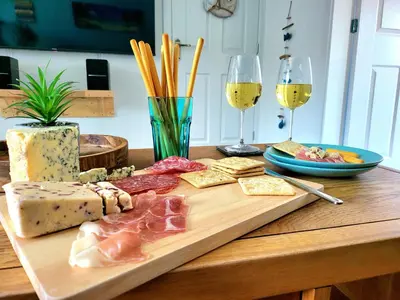 a cutting board with meat and cheese and two glasses of wine at Seaside beach themed home with garden and driveway in Lytham St Annes