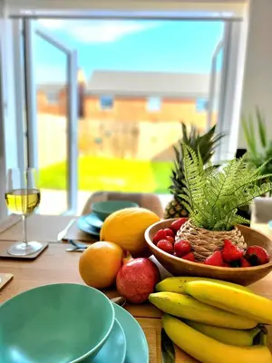 a table with a bowl of fruit and a glass of wine at Seaside beach themed home with garden and driveway in Lytham St Annes