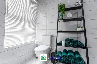 a bathroom with a toilet and a shelf with towels at Three Bedroom House in Preston in Preston