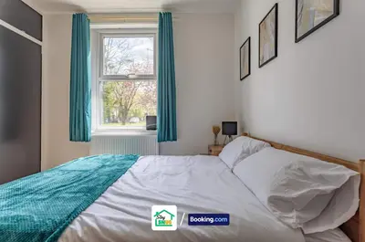 a bedroom with a bed with blue curtains and a window at Three Bedroom House in Preston in Preston