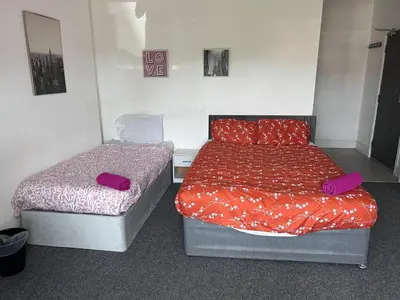 two beds in a small room with purple pillows at Triple room Private Bath Near LFC Free Street Parking No Breakfast in Liverpool