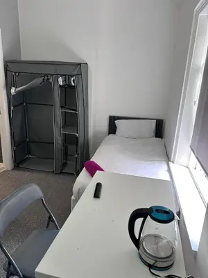 a small room with two beds and a table with a lamp at Triple room Private Bath Near LFC Free Street Parking No Breakfast in Liverpool