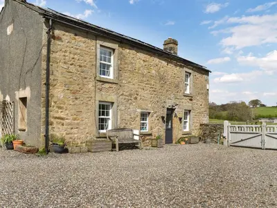 an old stone house with a bench in front of it at Box Tree Farmhouse - Uk47034 in Kirkby Lonsdale
