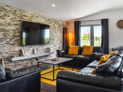 a living room with leather furniture and a brick wall at The Barbon - Uk47033 in Kirkby Lonsdale