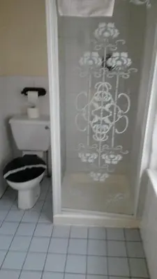 a bathroom with a toilet and a glass shower door at The Manuela Rose in Blackpool