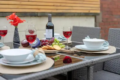a table with glasses of wine and plates of food at Kirkmoor Cottage - Cosy home central Clitheroe in Clitheroe
