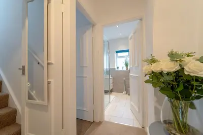 a hallway with a vase of flowers on a table at Kirkmoor Cottage - Cosy home central Clitheroe in Clitheroe