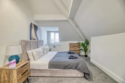 a bedroom with a bed and a table with a lamp at Fairhaven View by Guestz in Lytham St Annes