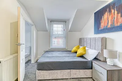 a bedroom with a bed with yellow pillows at Fairhaven View by Guestz in Lytham St Annes