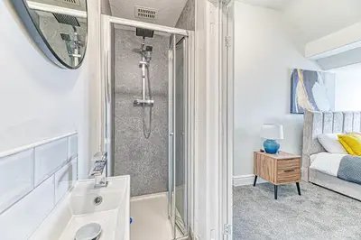 a bathroom with a shower and a sink and a bed at Fairhaven View by Guestz in Lytham St Annes