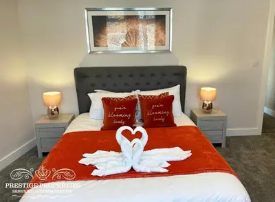 a bedroom with a bed with two swans forming a heart at Orange View by Prestige Properties SA in Haverigg