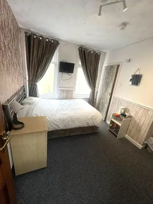 a bedroom with a large bed with a desk and windows at Tower Central hotel Albert Road in Blackpool