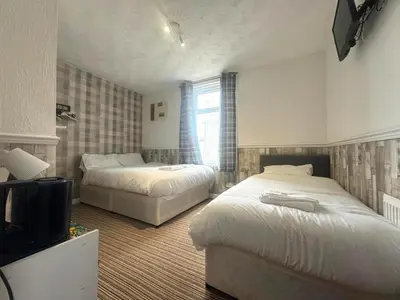 a bedroom with two beds and a tv in it at Tower Central hotel Albert Road in Blackpool