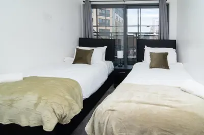 two beds in a room with a window at 2 bed 2 bath city centre sleep 7 in Liverpool