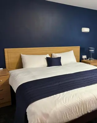 a bedroom with a large bed with a blue wall at Britannia Hotel Wigan in Standish