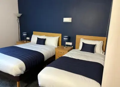 two beds in a hotel room with blue walls at Britannia Hotel Wigan in Standish