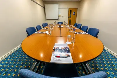 a conference room with a large wooden table and blue chairs at Britannia Hotel Wigan in Standish