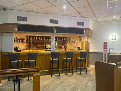 a bar in a restaurant with stools at Britannia Hotel Wigan in Standish