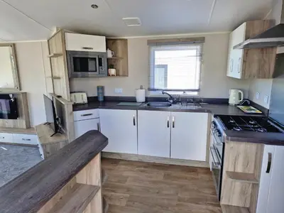 a kitchen with white cabinets and a stove top oven at Willaby skye in Heysham