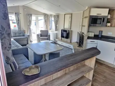 a kitchen and living room with a table in a room at Willaby skye in Heysham
