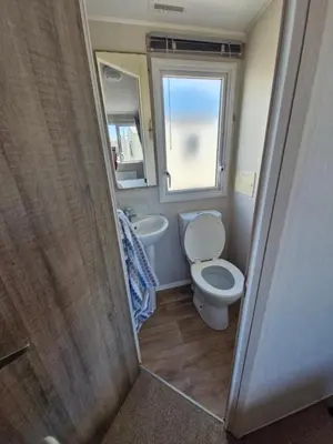 a bathroom with a toilet and a sink and a window at Willaby skye in Heysham