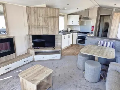 a kitchen with a living room with a table and a tv at Willaby skye in Heysham