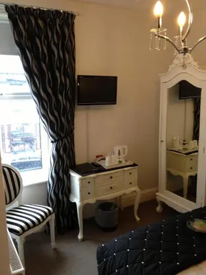 a room with a bed and a dresser and a mirror at Glen Guest House in Blackpool