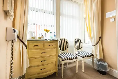 a bedroom with a dresser and two chairs next to a window at Glen Guest House in Blackpool
